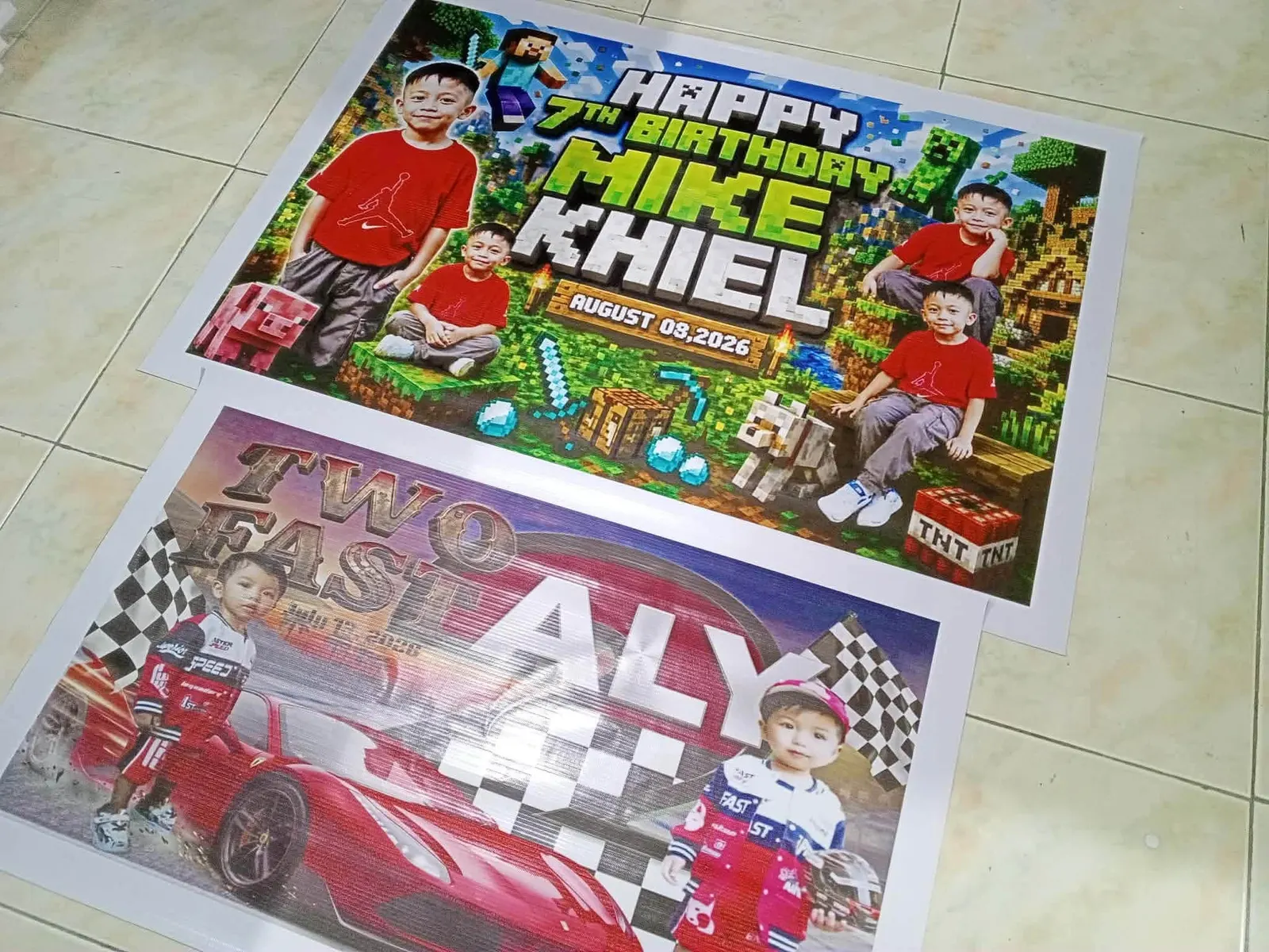 Two birthday tarpaulins, one with a game theme and one with a racing theme