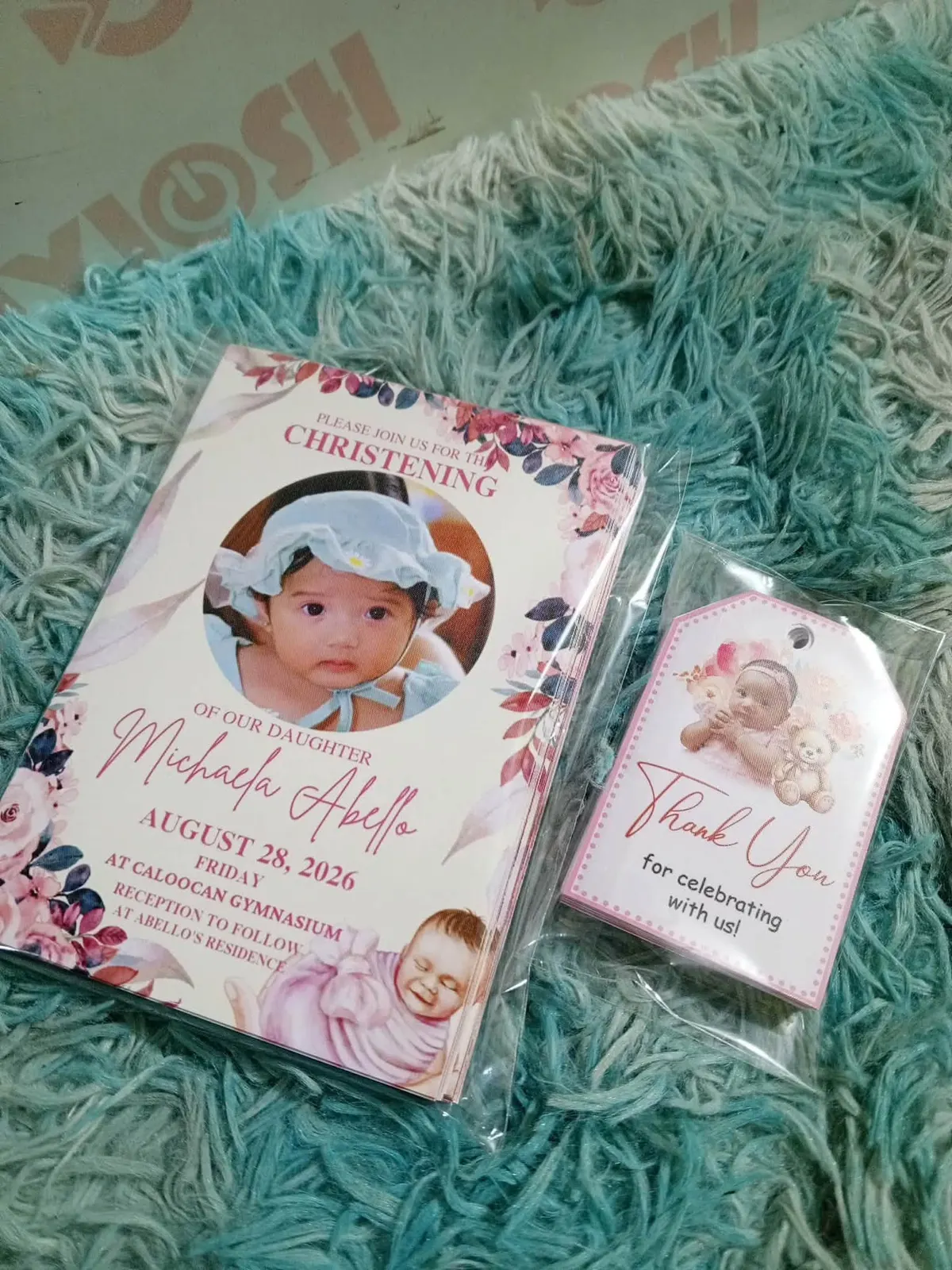 A stack of christening invitations beside a packed thank-you tag