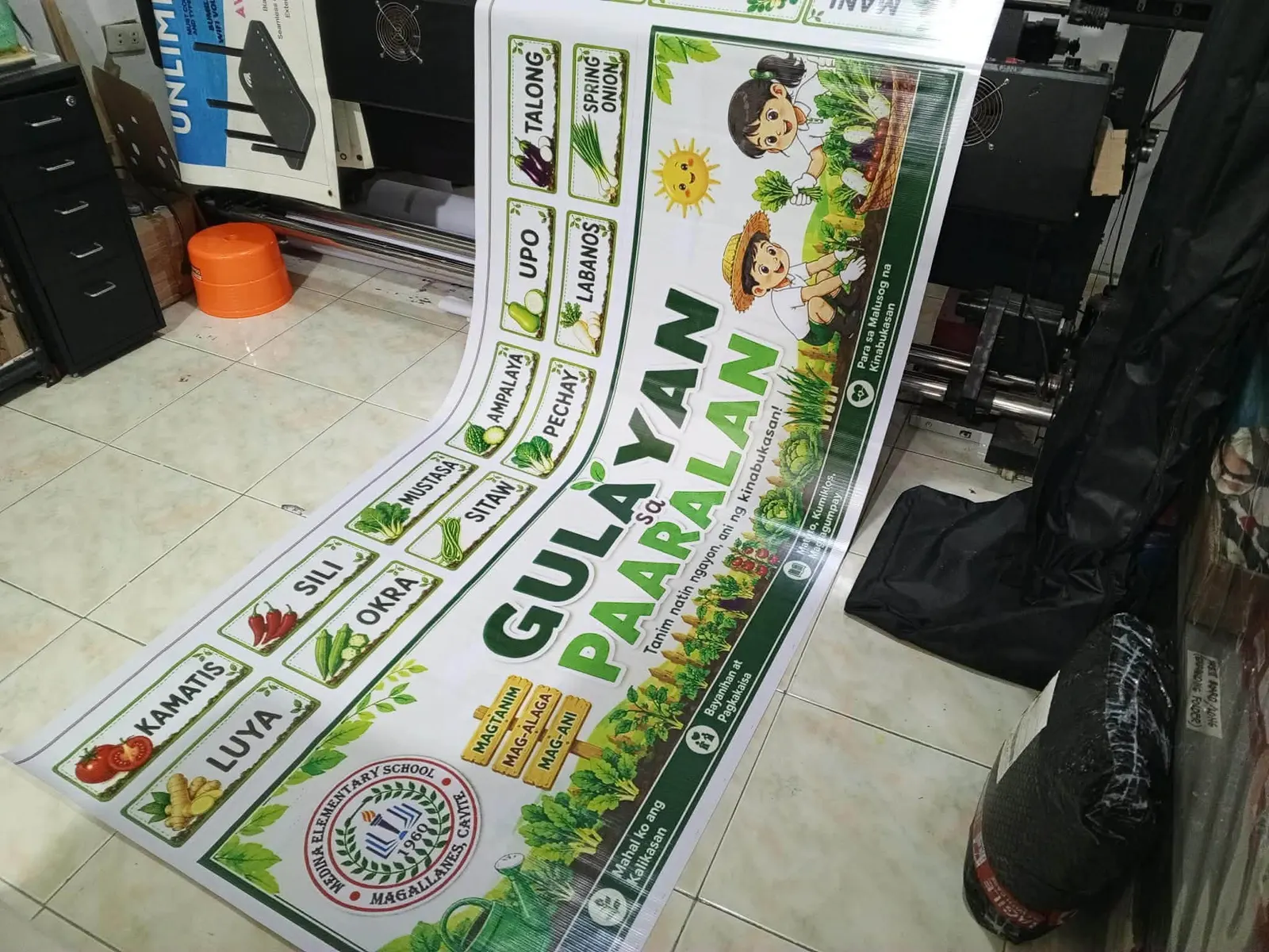 Long school banner about a vegetable garden, coming off the printer